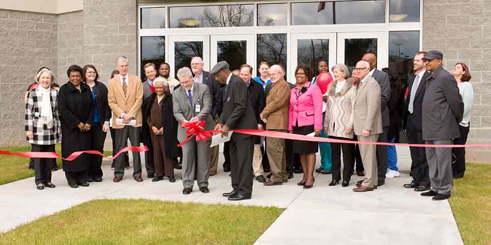 Men cutting a ribbon in front of the Biotechnology and Medical Simulation Center 