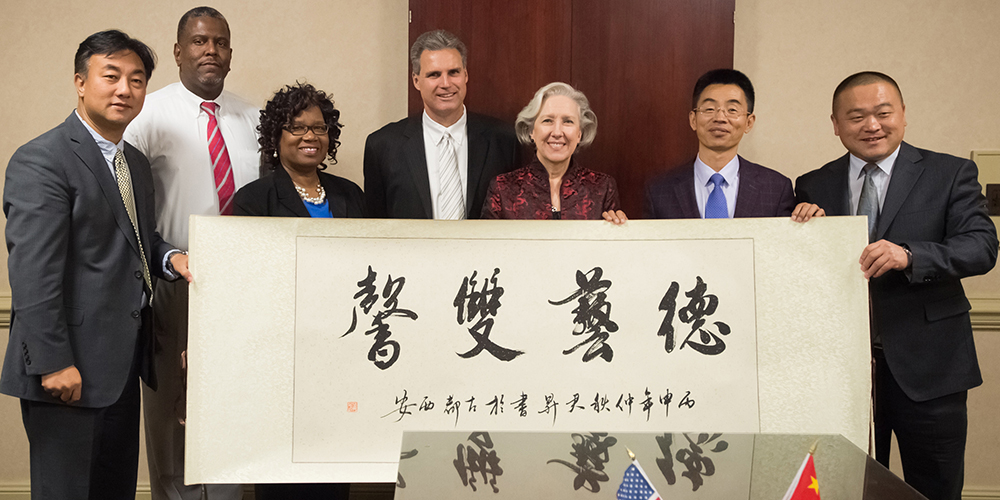 Representatives from Edgecombe Community College, the Shaanxi Provincial Tourism School, and the Global Classroom Alliance met on ECC’s Tarboro campus recently to sign an agreement that will lead to exchange opportunities. From left are officials of the institutions: Shui Jing, Tony Rook, Viola Harris, Dr. Harry Starnes, Dr. Deborah Lamm, Zhang Junsheng, and Liu Jizhong. The translation of the symbols on the banner, which was presented to ECC by the Chinese delegation, is “Mutual benefit in morality and of academics.”