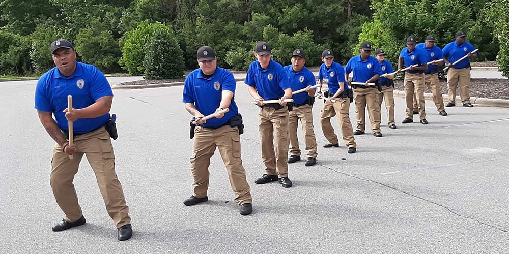 Ten basic law enforcement cadets lined in tactical position with batons.