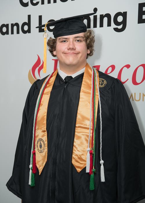 Smiling white male with curly hair wearing cap and gown with stole and cords.
